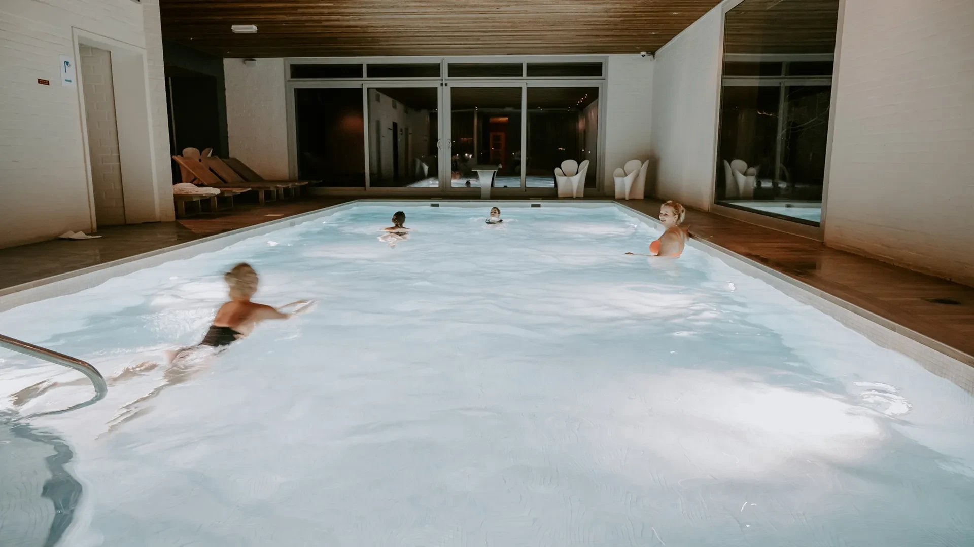 Piscine intérieure avec personnes nageant et se relaxant.