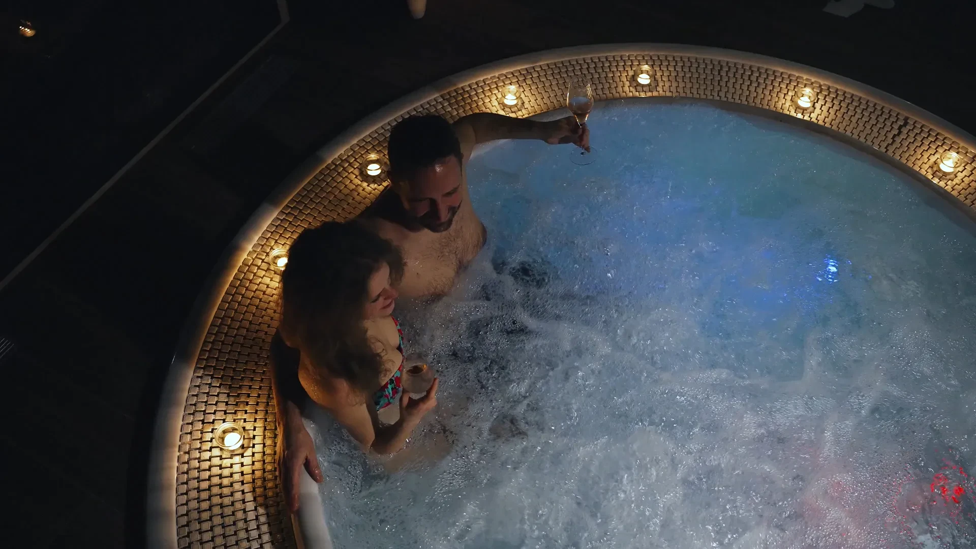 Couple dans un jacuzzi avec des verres de vin.