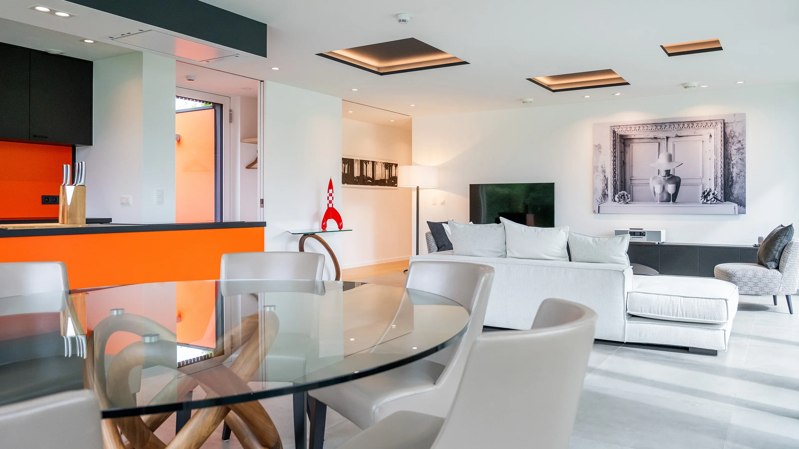 Salon moderne avec cuisine ouverte et déco artistique.