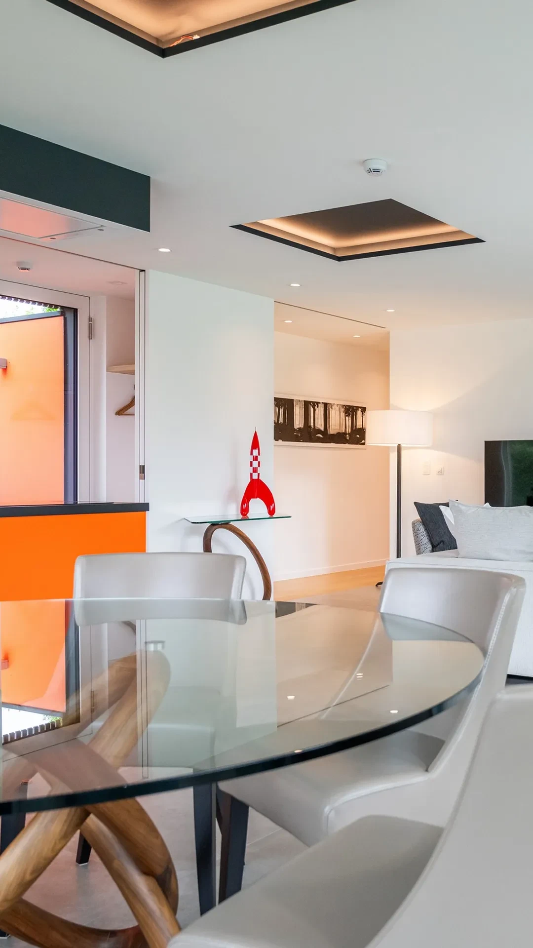 Salon moderne avec table en verre et décorations.