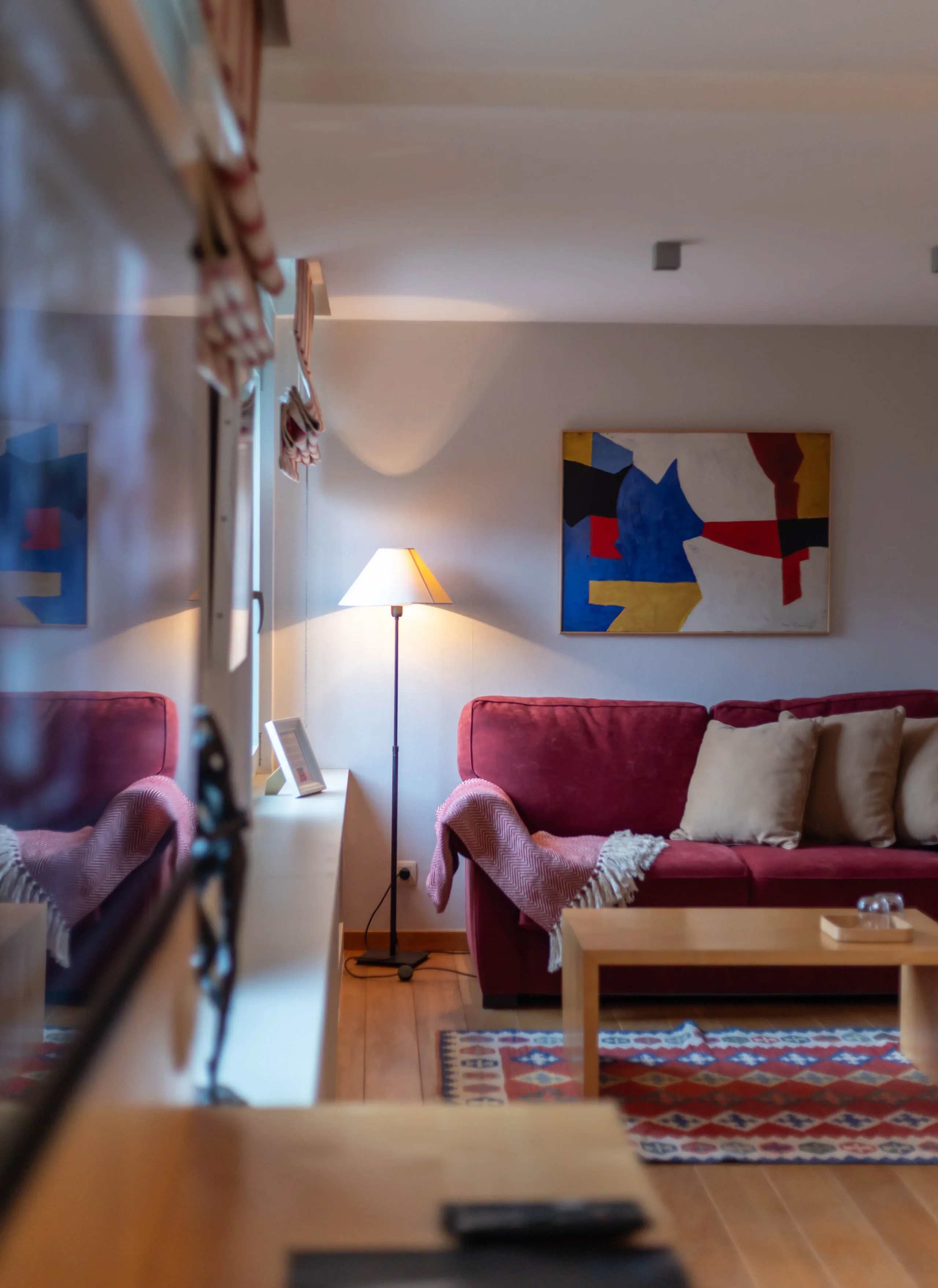 Salon moderne avec canapé rouge et lampe allumée.