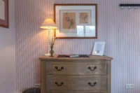 Commode en bois sous lampe et tableau.