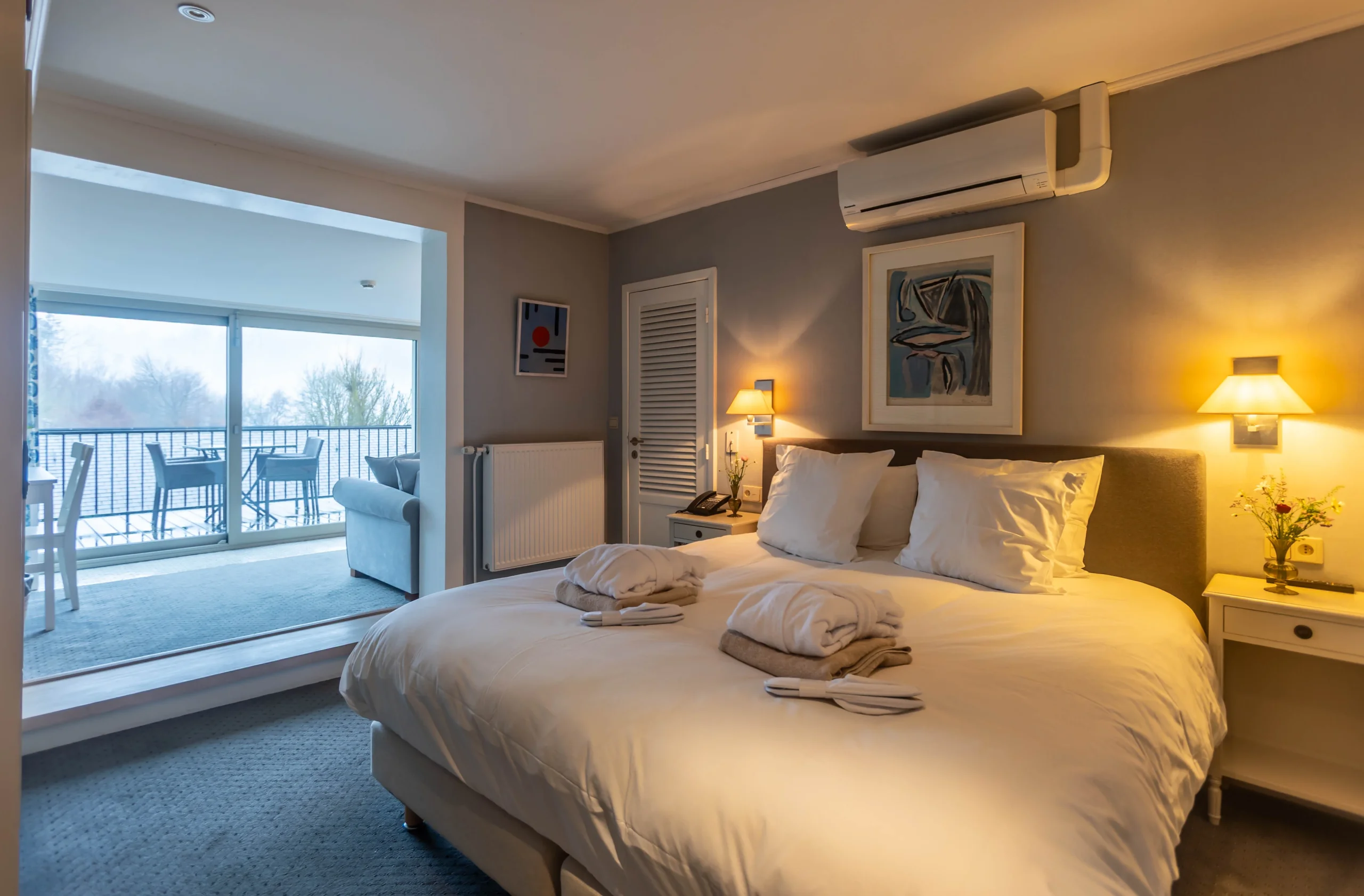 Chambre d'hôtel lumineuse avec lit double et balcon.