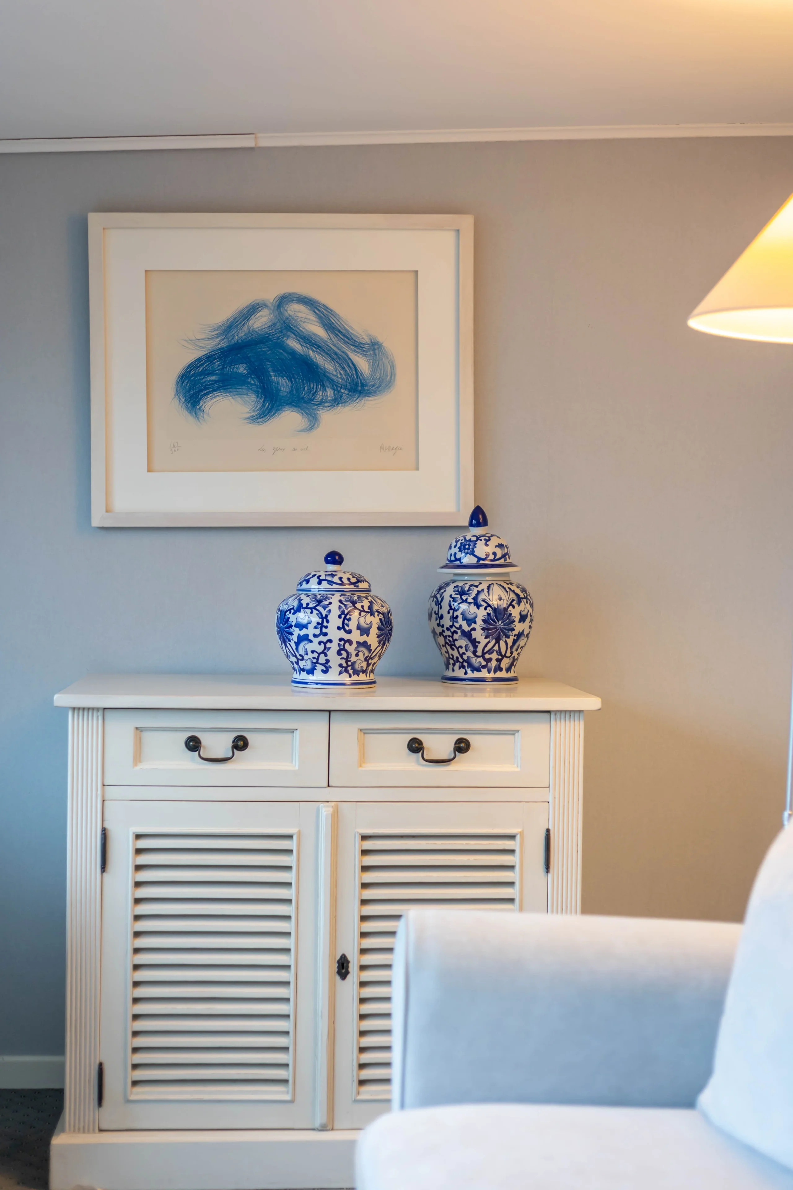 Commode blanche avec vases bleus décoratifs.
