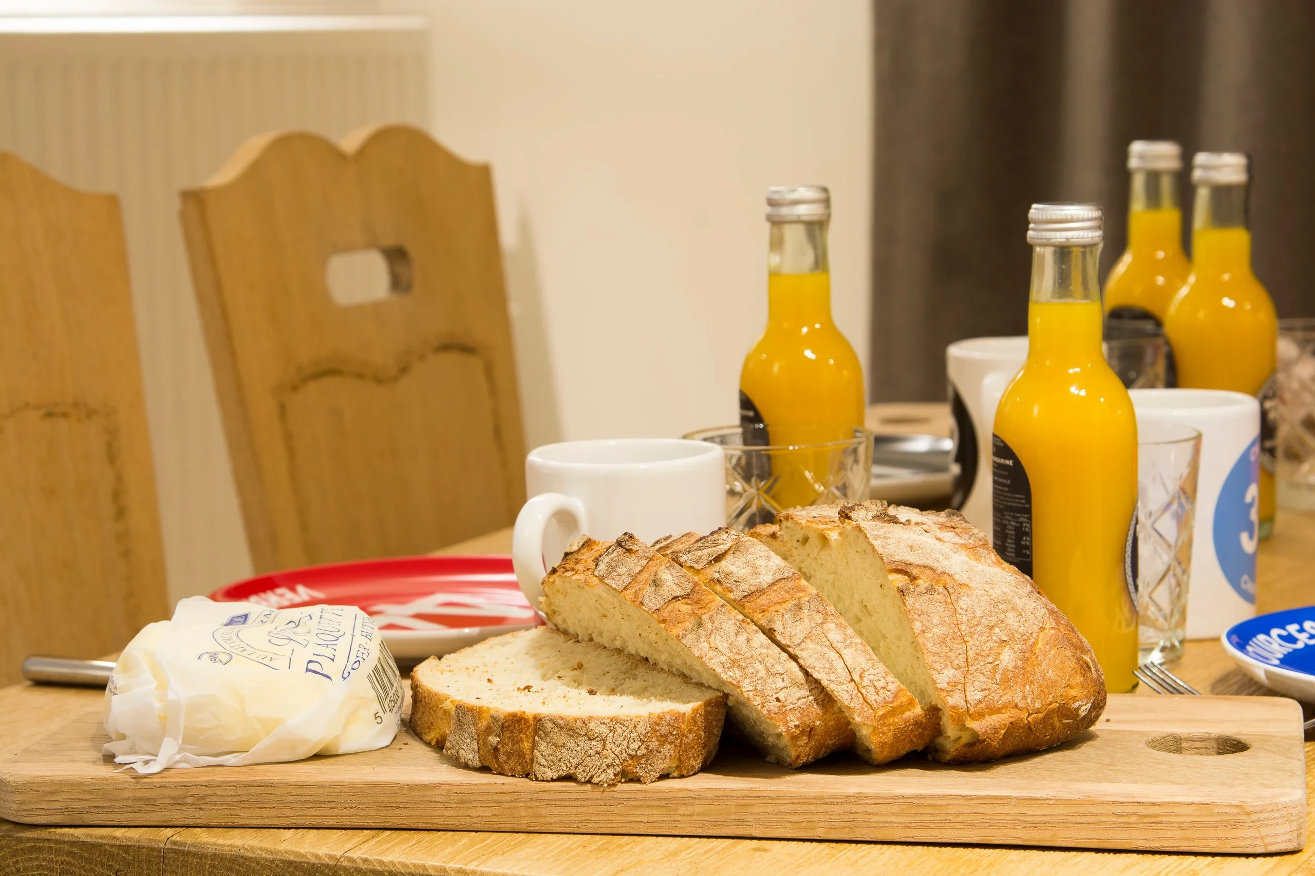 Petit-déjeuner avec pain, beurre, jus d'orange et café.