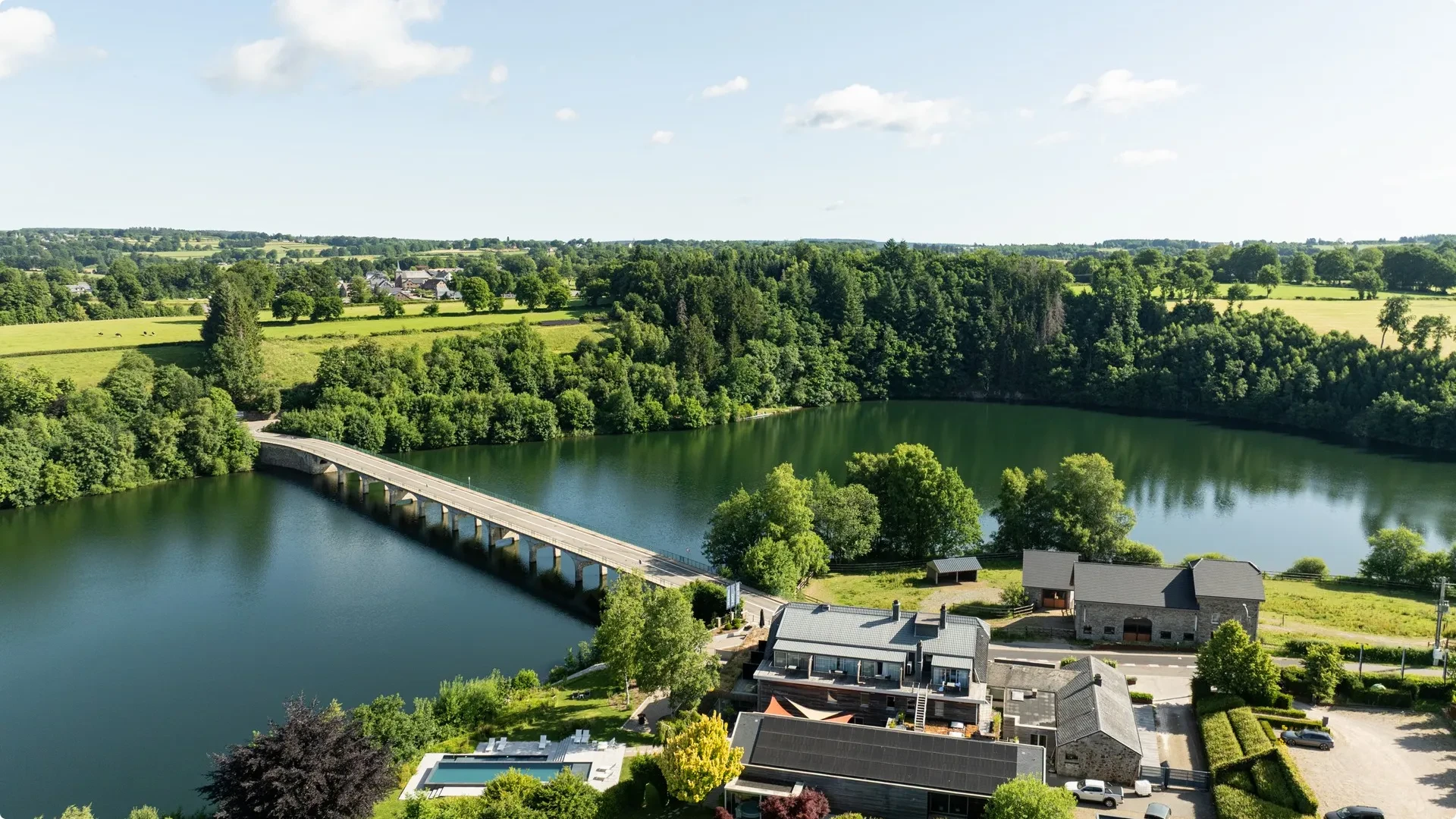 Vue aérienne du lac et pont entourés de nature.