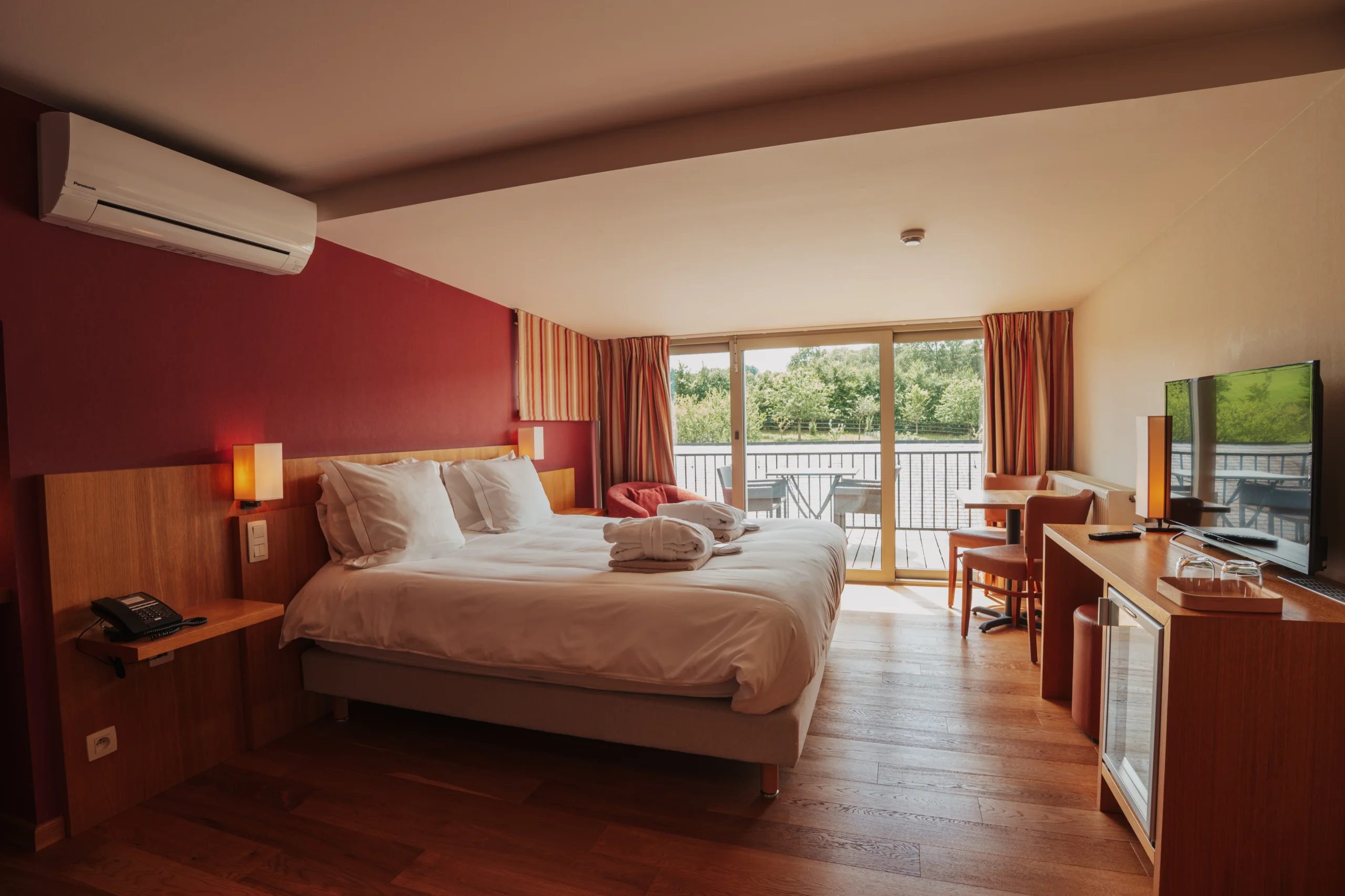 Chambre d'hôtel moderne avec balcon et vue jardin.