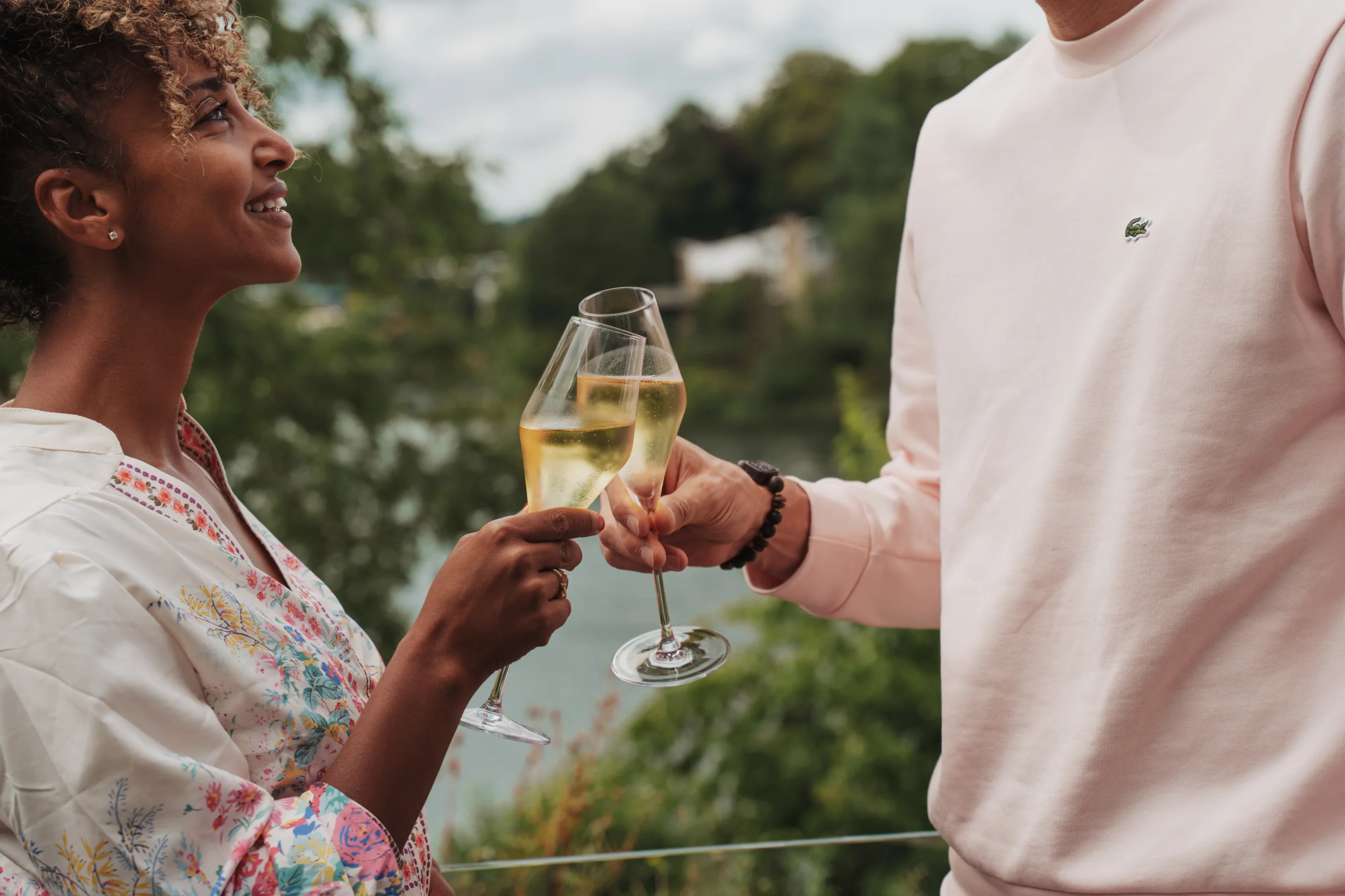 Couple trinque avec du champagne en extérieur.
