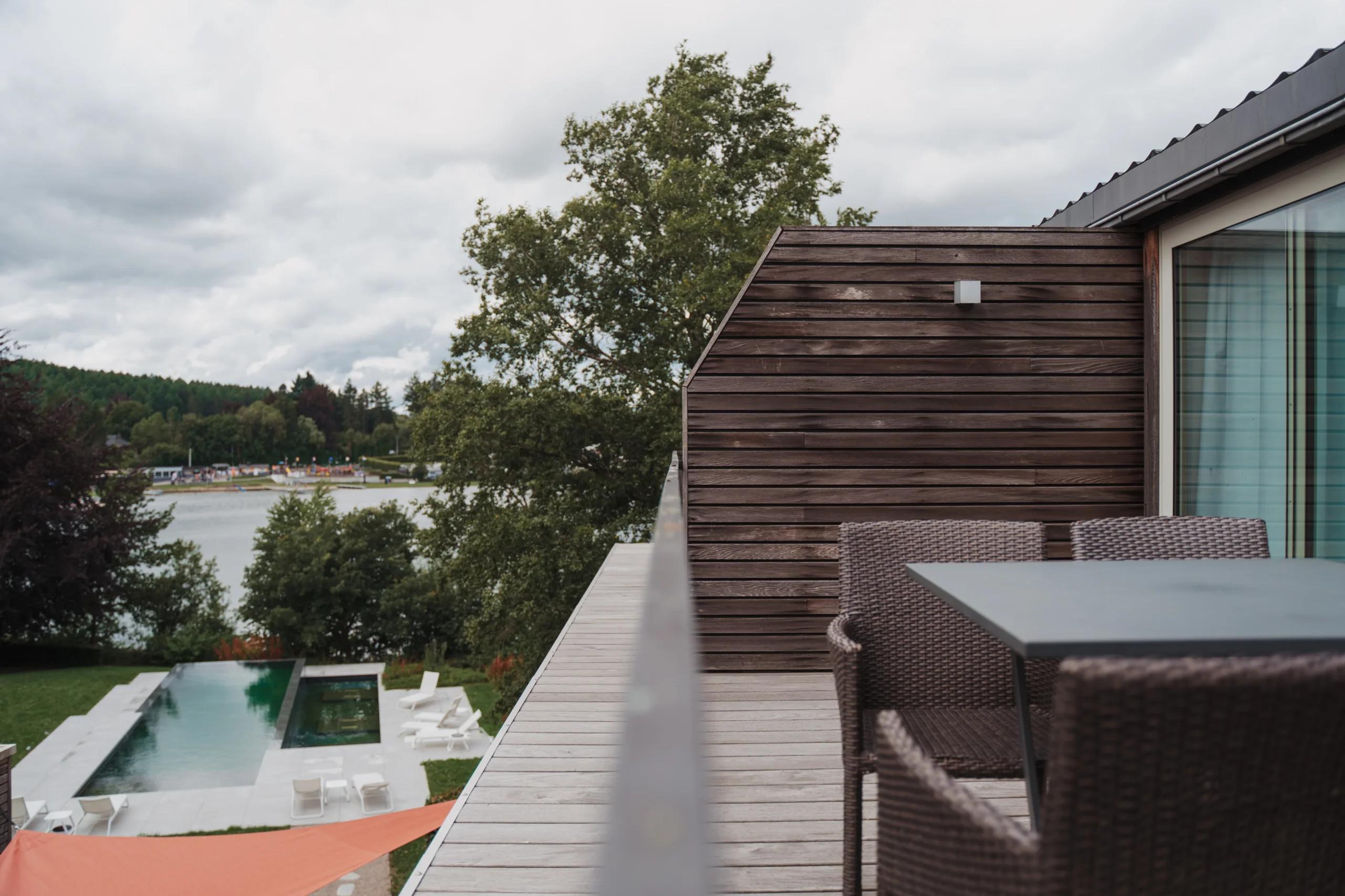 Terrasse en bois avec vue sur la piscine et lac.