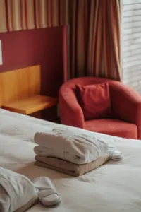 Chambre d'hôtel avec peignoirs et fauteuil rouge.
