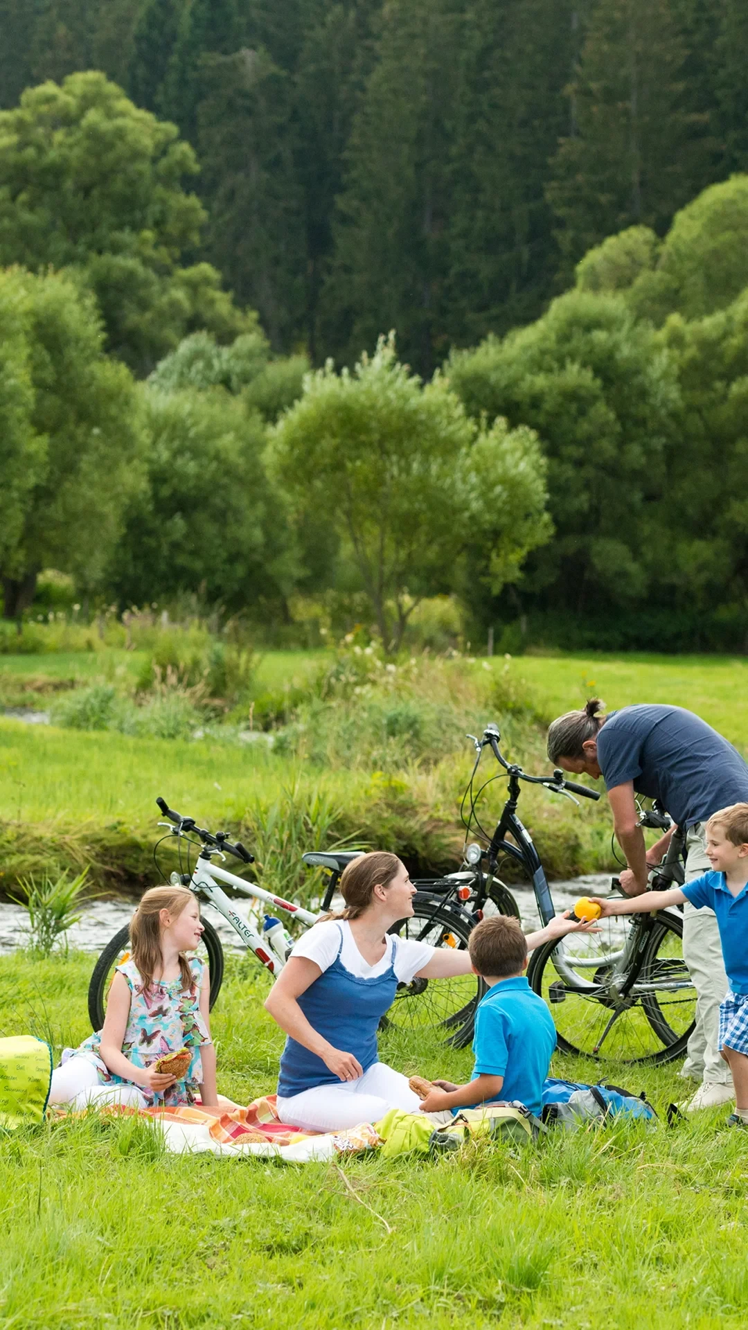 Famille pique-niquant dans un parc avec des vélos - Séjour Wellness Belgique - Robert Hôtels