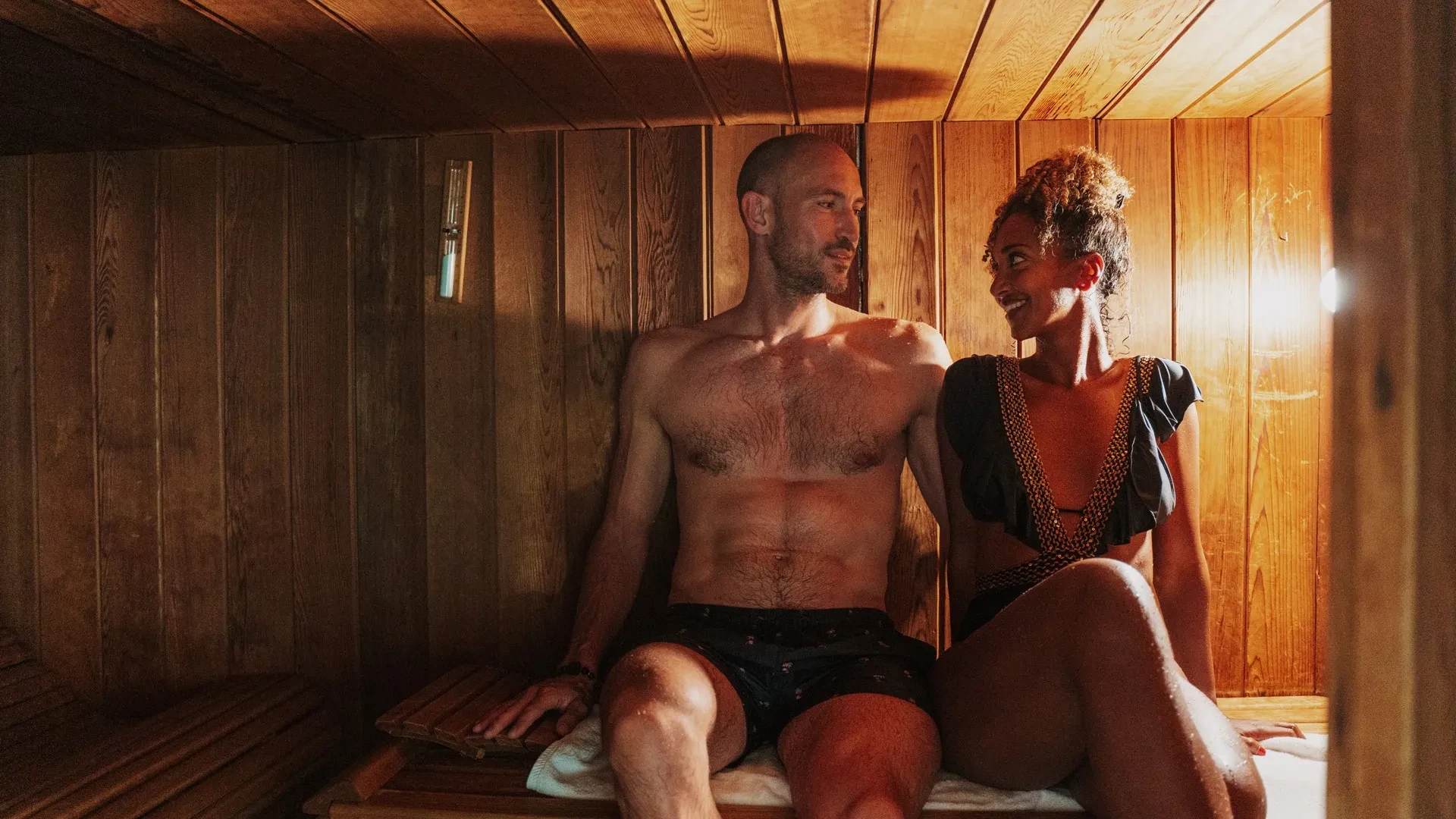 Couple relaxant ensemble dans un sauna en bois.