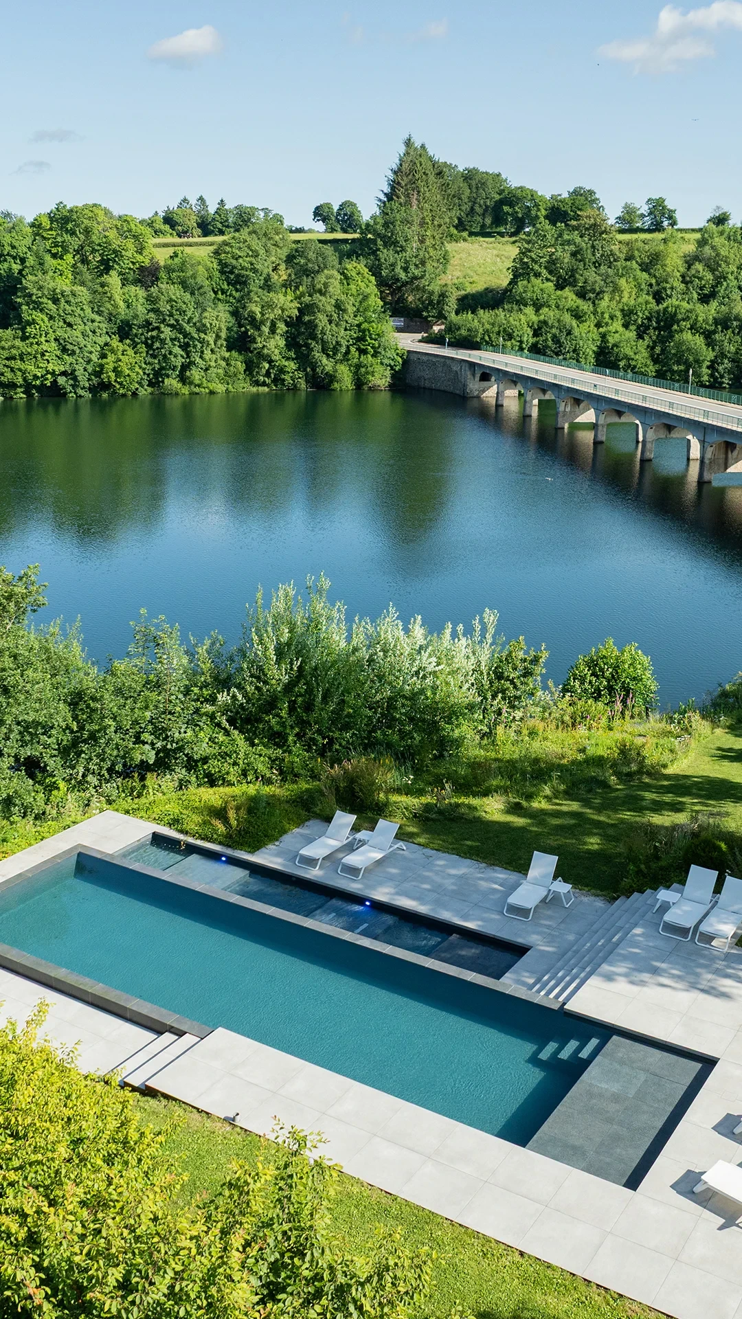 Vue sur piscine et lac entouré de verdure.