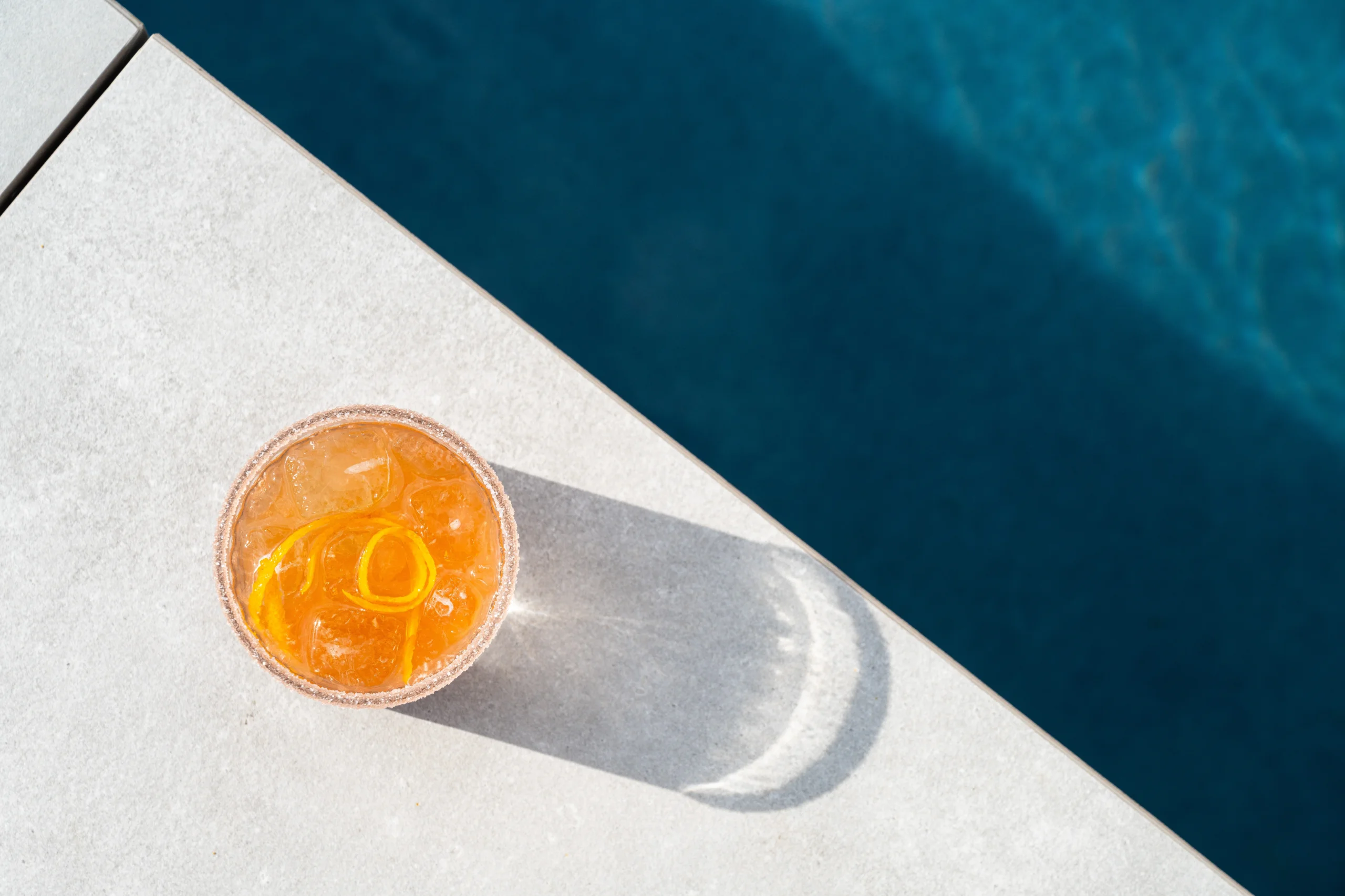 Cocktail orange sur une terrasse près d'une piscine.