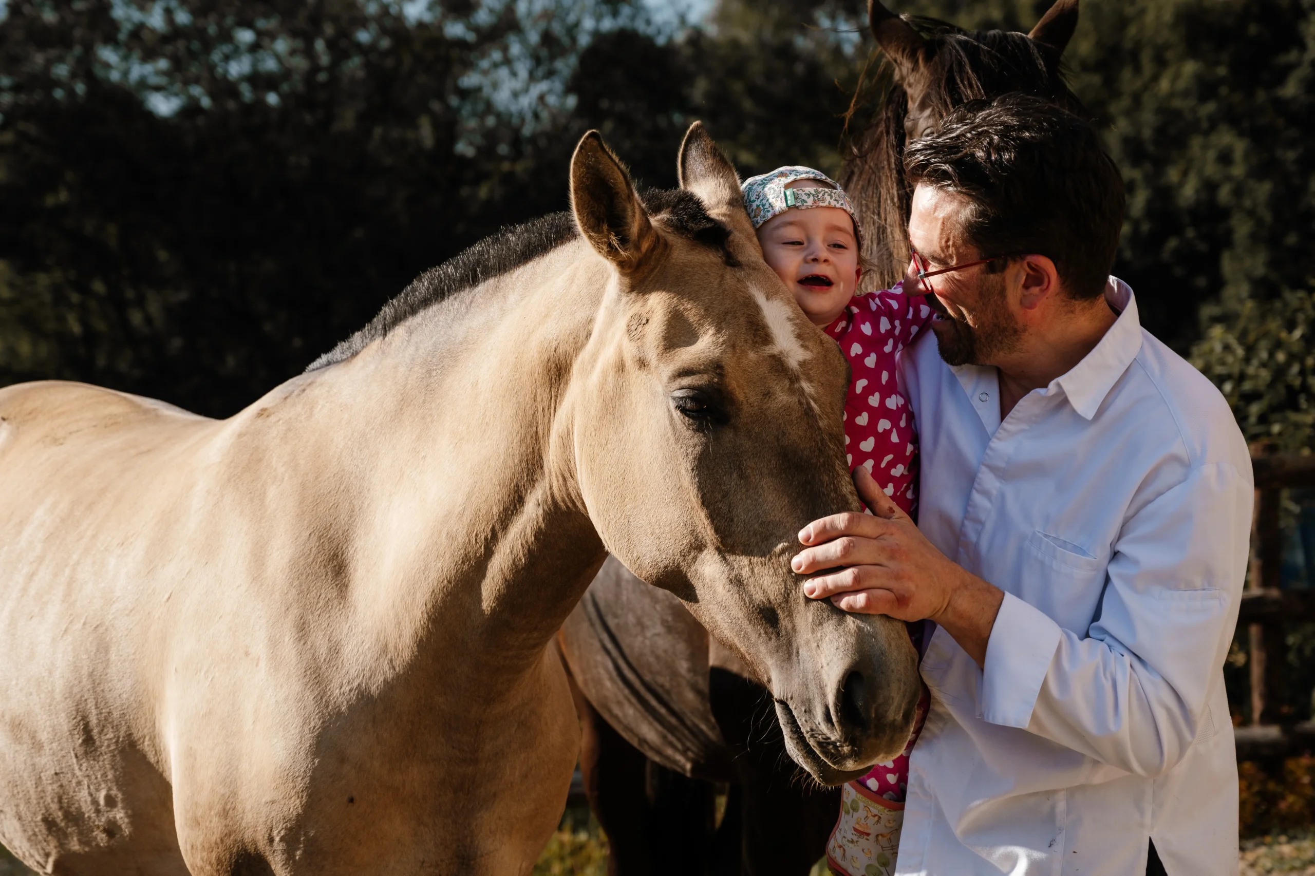 Homme et enfant caressant un cheval sous le soleil.
